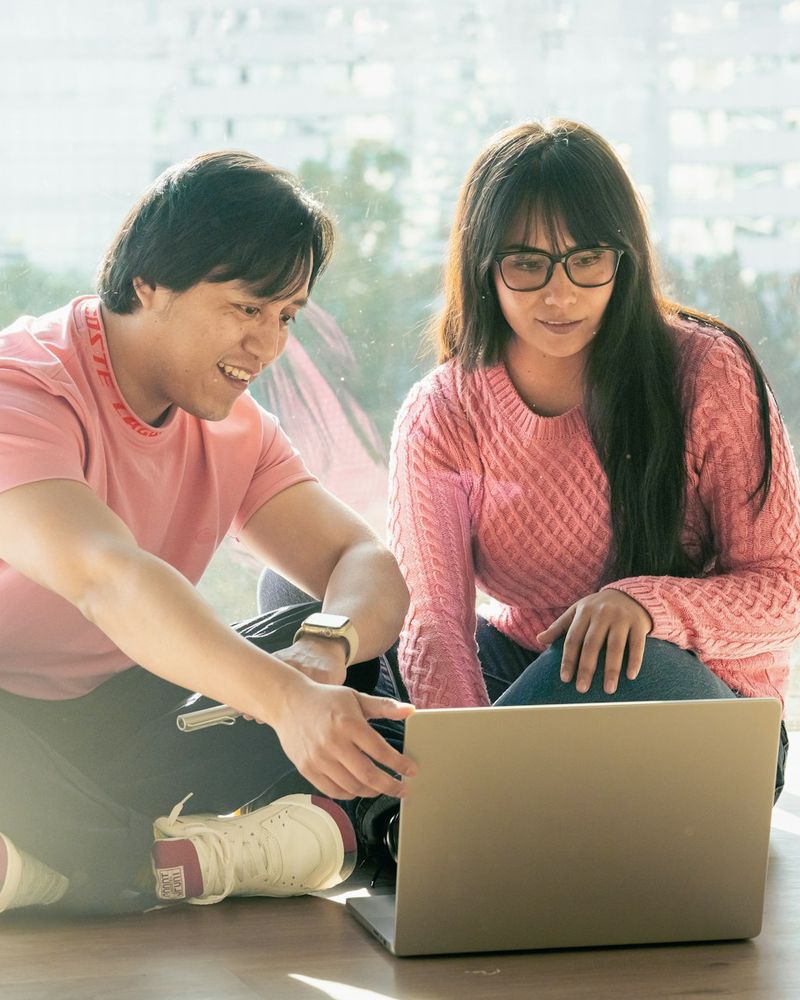 A couple sitting on the floor planning together on a laptop